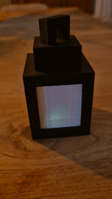 Zwarte 3D-geprinte Minecraft-lantaarn met gekleurd licht op een houten tafel